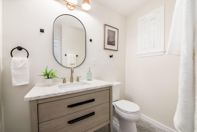 bathroom with toilet, vanity, and baseboards