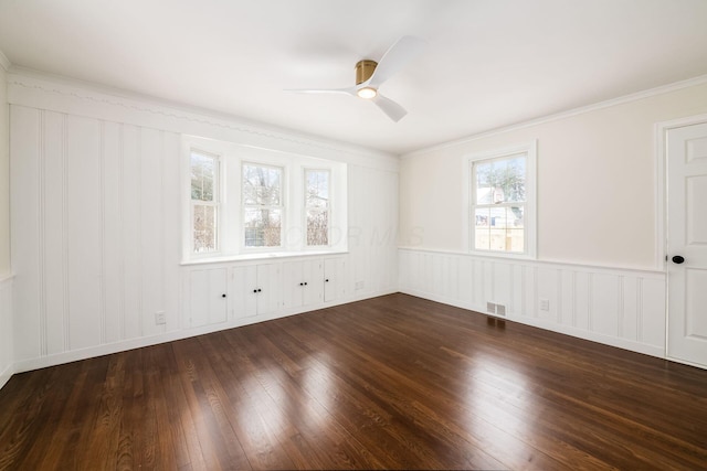 spare room with ornamental molding, dark wood-style flooring, visible vents, and a ceiling fan