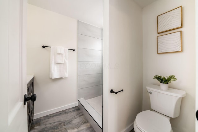 bathroom with toilet, baseboards, a tile shower, and vanity