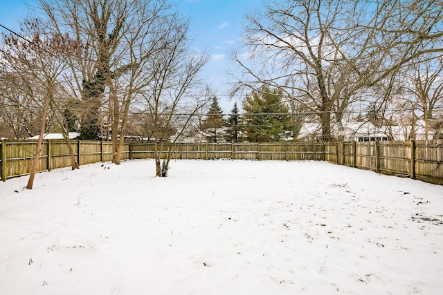 yard layered in snow with a fenced backyard