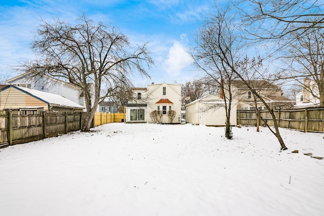 snowy yard featuring an outbuilding and a fenced backyard