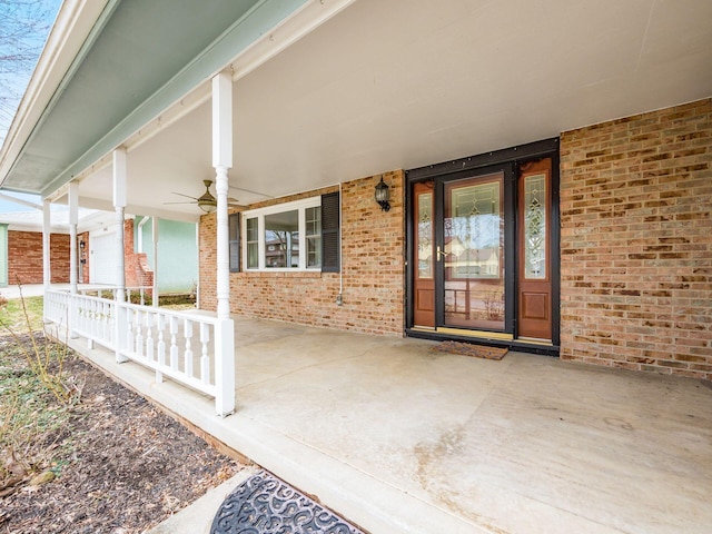 doorway to property featuring a porch and brick siding