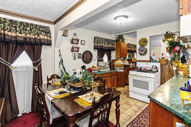 kitchen featuring white range with gas stovetop, brown cabinets, and a textured ceiling