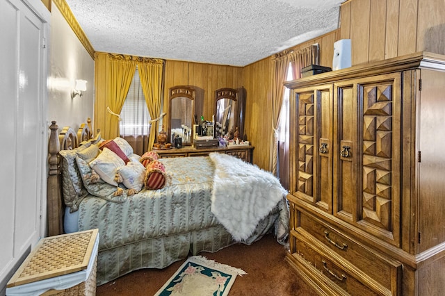 bedroom featuring wooden walls, dark colored carpet, and a textured ceiling