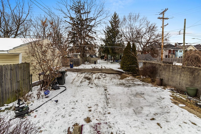 yard layered in snow with a residential view and fence