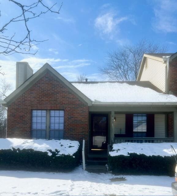 view of front facade featuring a chimney and brick siding