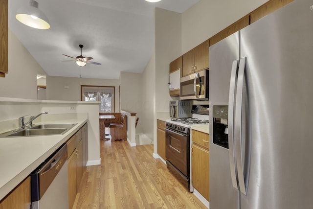 kitchen featuring a sink, a ceiling fan, light countertops, appliances with stainless steel finishes, and light wood-type flooring