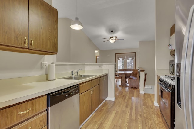 kitchen with stainless steel appliances, a sink, light countertops, and brown cabinets