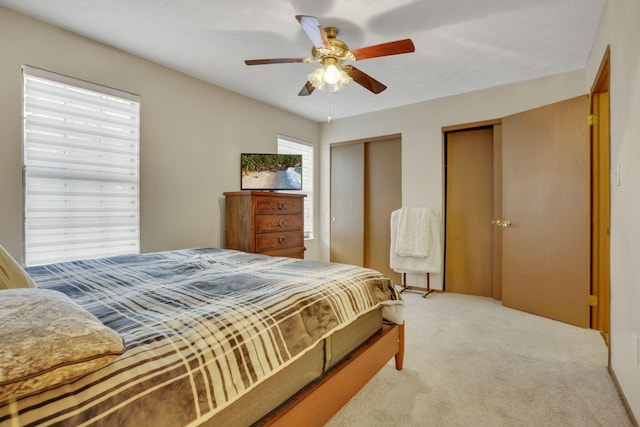 carpeted bedroom with ceiling fan and two closets