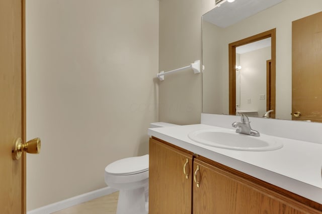 bathroom featuring baseboards, vanity, and toilet