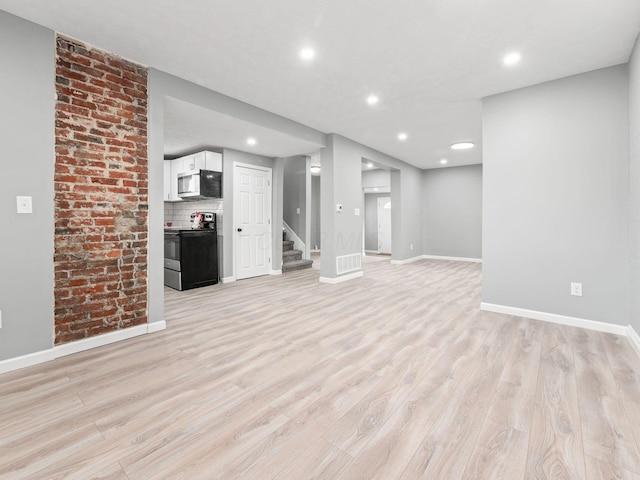 basement with light wood-style flooring, stairs, and baseboards