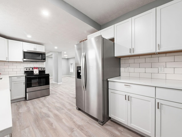 kitchen featuring tasteful backsplash, light wood-style flooring, appliances with stainless steel finishes, light countertops, and white cabinetry