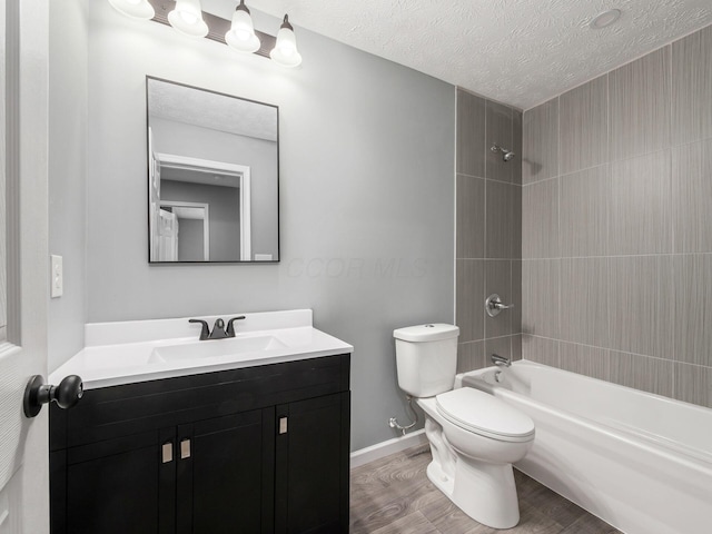 full bathroom featuring a textured ceiling, toilet, wood finished floors, vanity, and tub / shower combination