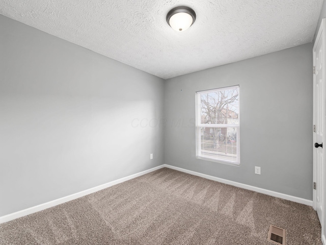 carpeted empty room with visible vents, a textured ceiling, and baseboards