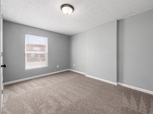 unfurnished room with a textured ceiling, carpet, and baseboards