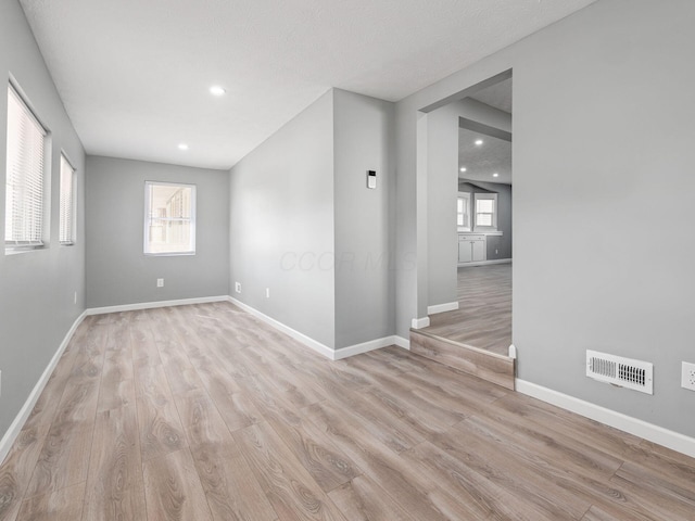 unfurnished room featuring light wood-style floors, baseboards, visible vents, and recessed lighting