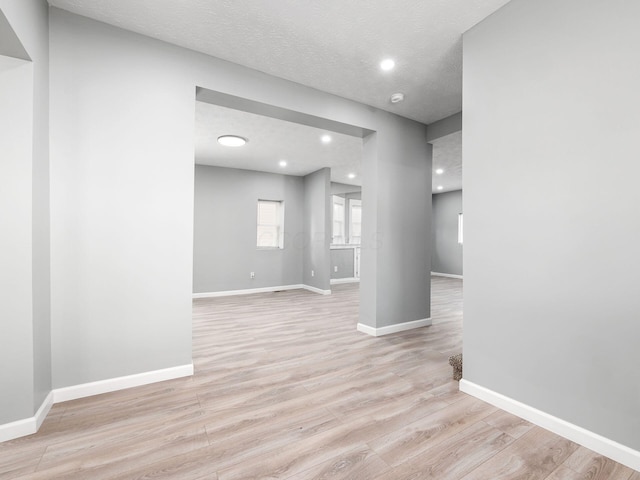 spare room with recessed lighting, light wood-style flooring, baseboards, and a textured ceiling