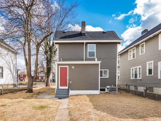 back of property featuring entry steps, a chimney, fence, and cooling unit