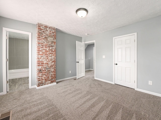 unfurnished bedroom with carpet floors, connected bathroom, a textured ceiling, and baseboards