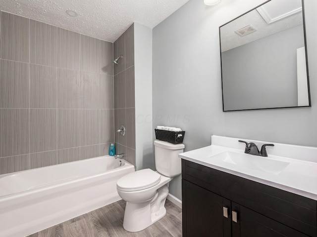 bathroom featuring visible vents, toilet, washtub / shower combination, a textured ceiling, and wood finished floors