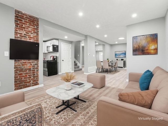 living area with light wood finished floors, recessed lighting, visible vents, baseboards, and stairs