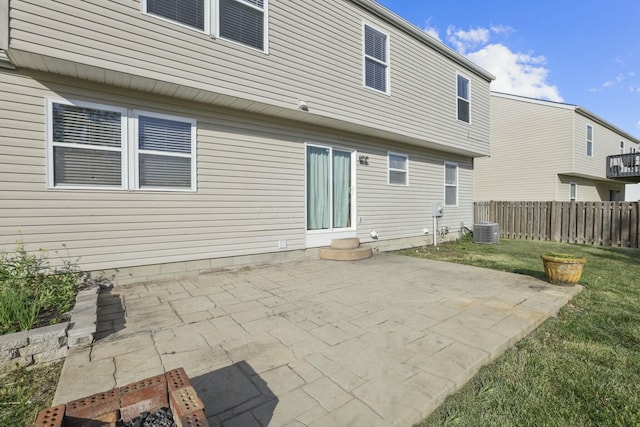 rear view of property featuring entry steps, cooling unit, fence, a lawn, and a patio area