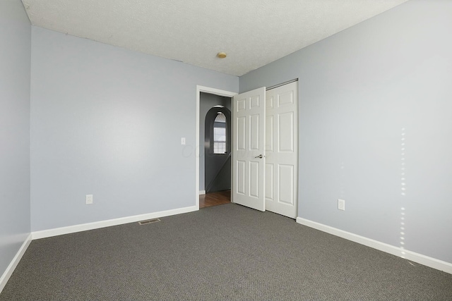 empty room with visible vents, baseboards, and dark colored carpet