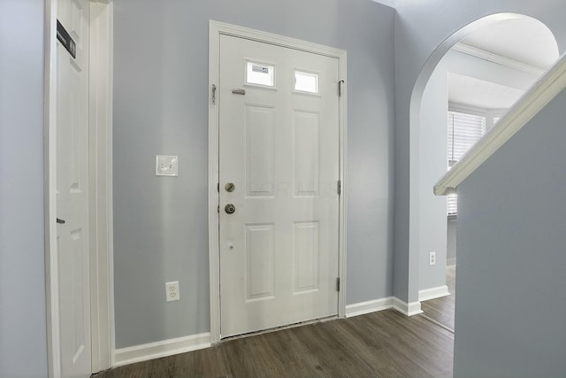 foyer featuring dark wood-style floors, arched walkways, and baseboards