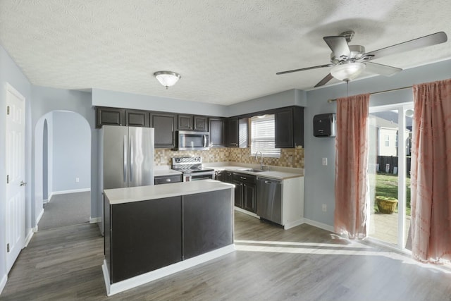 kitchen featuring a sink, stainless steel appliances, a kitchen island, and light countertops