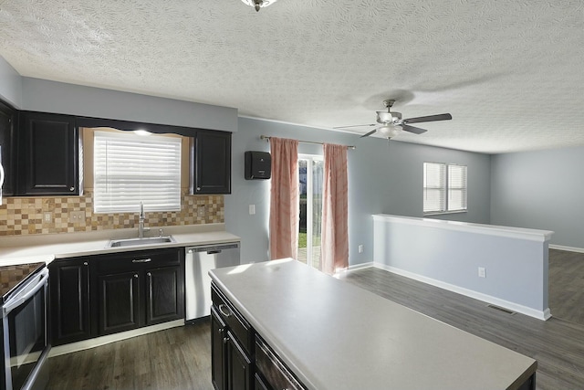 kitchen featuring dark wood finished floors, appliances with stainless steel finishes, a sink, light countertops, and backsplash