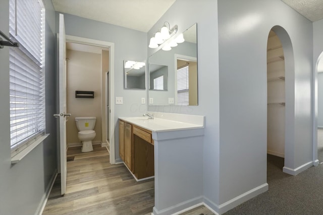 bathroom with toilet, baseboards, wood finished floors, and vanity