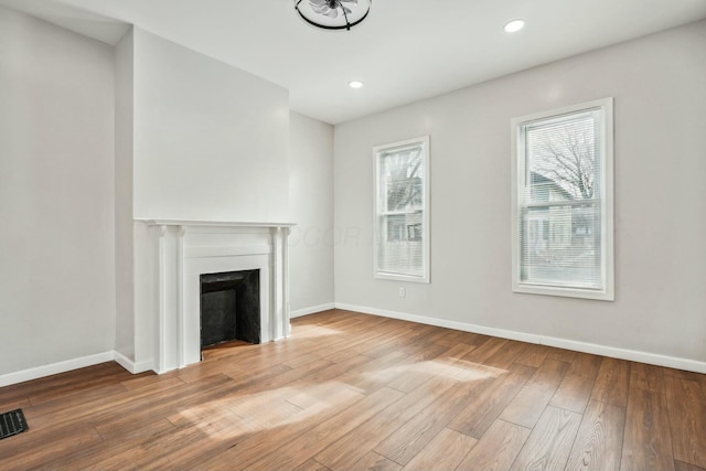 unfurnished living room featuring a fireplace, baseboards, wood finished floors, and recessed lighting