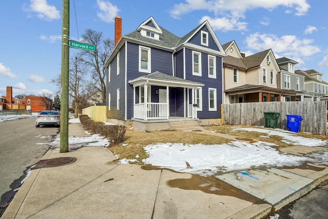 view of front of home with a porch, a residential view, fence, and a chimney