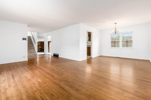 2715 Kenview Rd S, Columbus, OH 43209 - unfurnished living room featuring stairs, wood finished floors, baseboards, and a notable chandelier