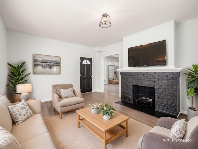 living room featuring a brick fireplace, light wood-style flooring, and baseboards