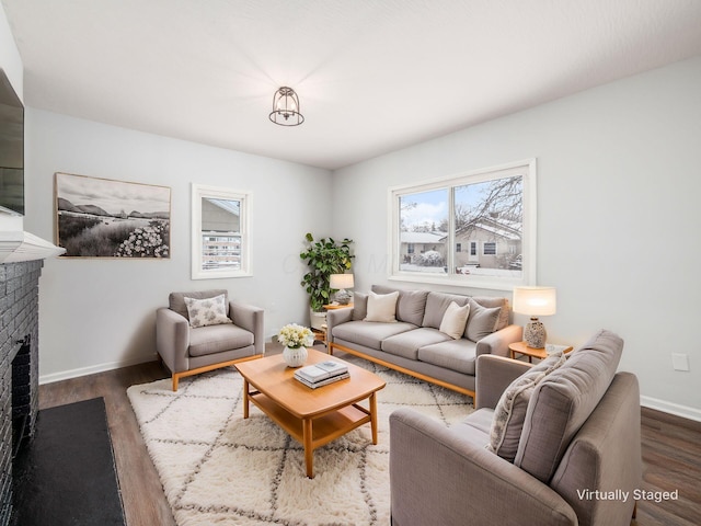 living room featuring a brick fireplace, wood finished floors, and baseboards