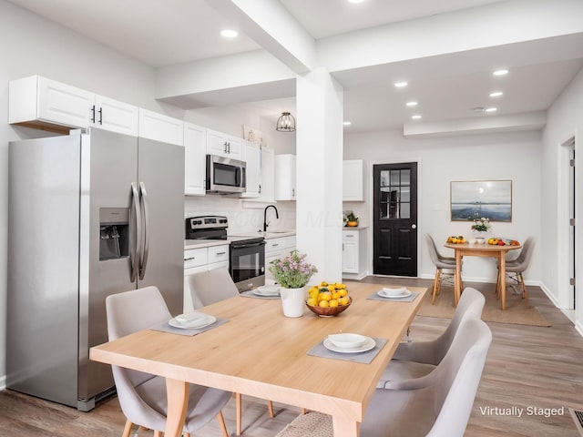 dining space with baseboards, light wood finished floors, and recessed lighting