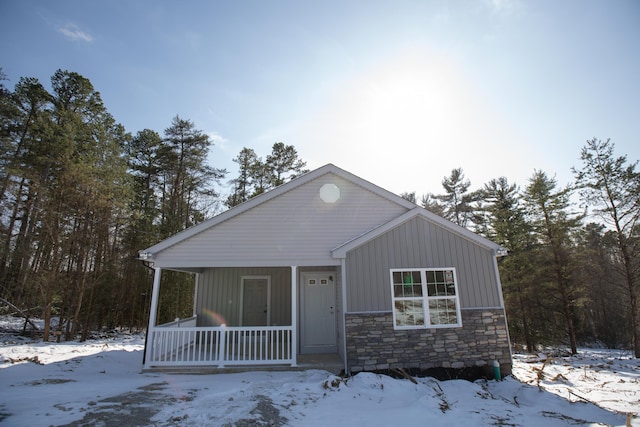 view of front facade with a porch, stone siding, and board and batten siding