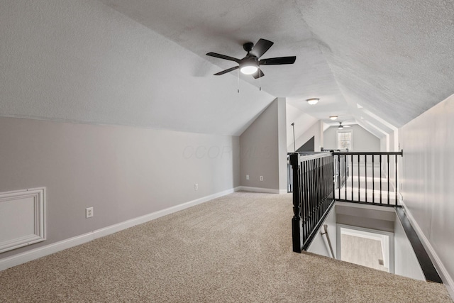 bonus room featuring carpet, vaulted ceiling, a textured ceiling, and baseboards