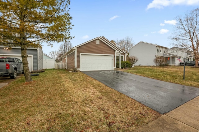 view of front of property with a detached garage, fence, an outbuilding, and a front yard