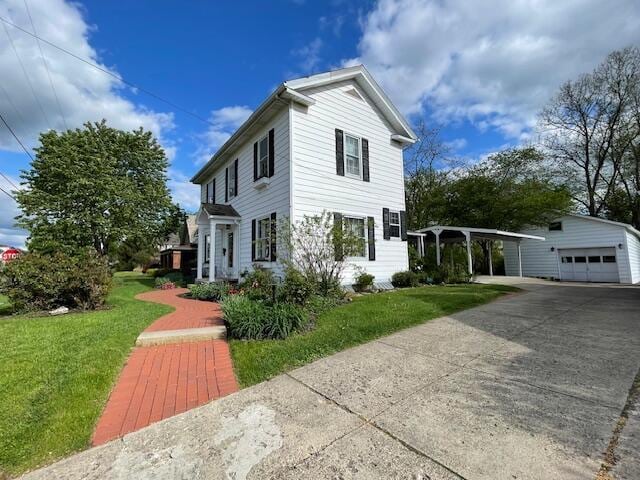 view of front of home with driveway, a carport, an outbuilding, a front lawn, and a garage