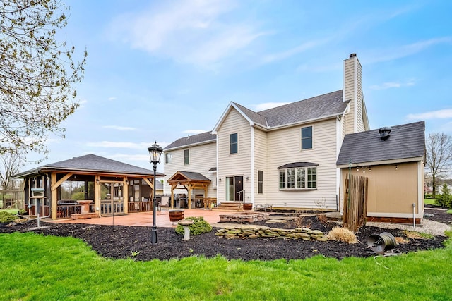 rear view of property featuring a gazebo, roof with shingles, a patio, and a chimney