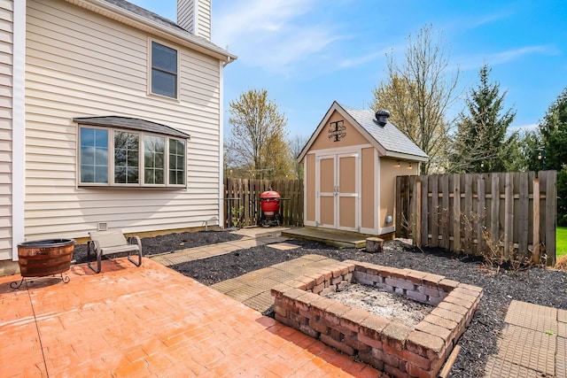 view of patio with a fire pit, an outdoor structure, fence, and a storage shed