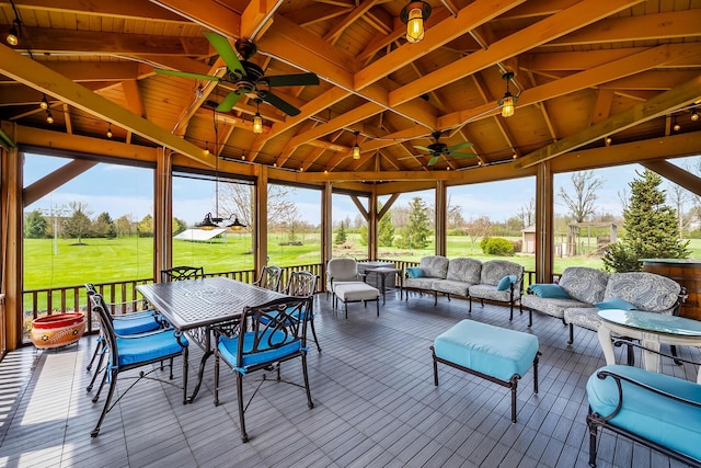 sunroom with outdoor dining area and a ceiling fan