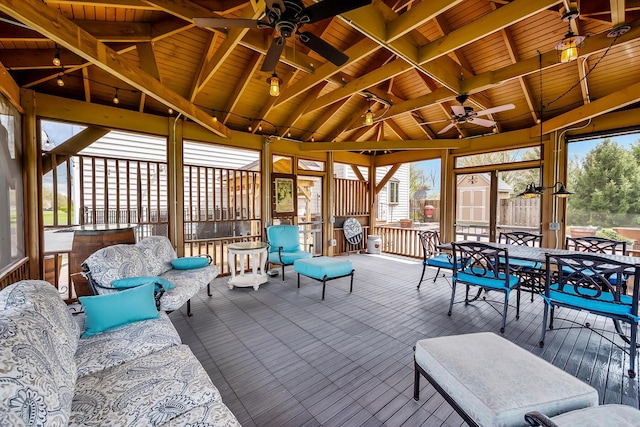 sunroom with ceiling fan, beam ceiling, and outdoor dining space