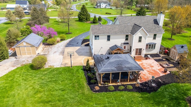 rear view of house with a chimney, an outdoor structure, and a lawn
