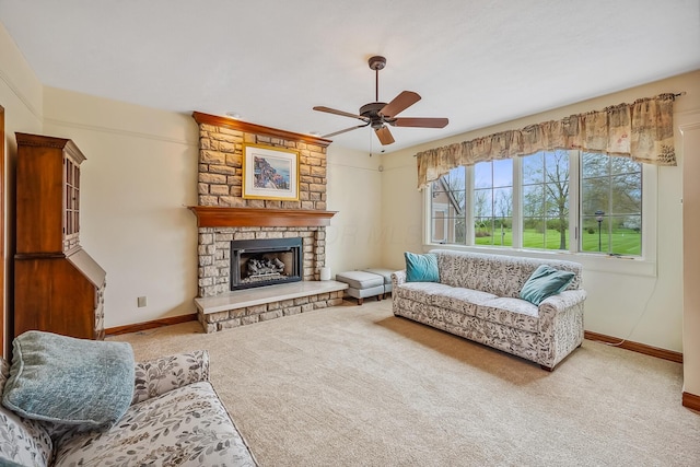 living area featuring ceiling fan, baseboards, a stone fireplace, and carpet