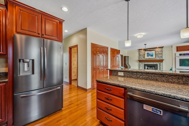 kitchen featuring light wood-type flooring, stainless steel refrigerator with ice dispenser, dishwasher, and pendant lighting