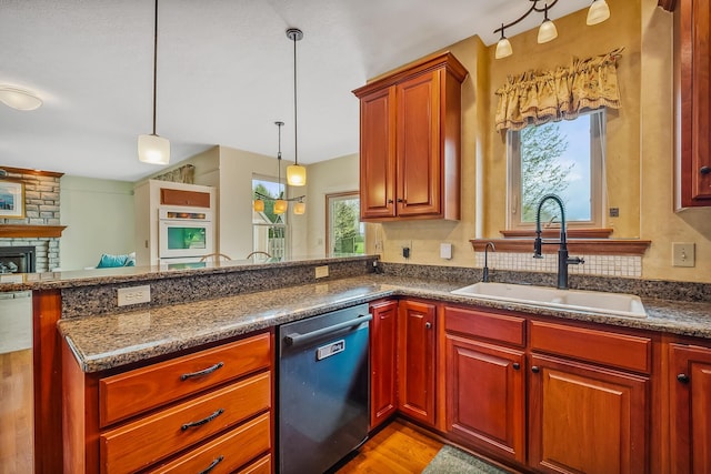 kitchen with a peninsula, dishwasher, a healthy amount of sunlight, and a sink