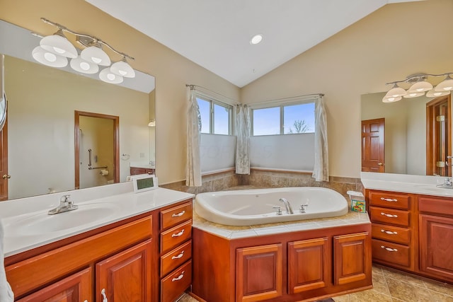 bathroom featuring a bath, lofted ceiling, a sink, and two vanities